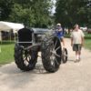 Man walking beside man driving tractor at the Tri-State Antique Gas Engine Tractor Show in Portland, Indiana