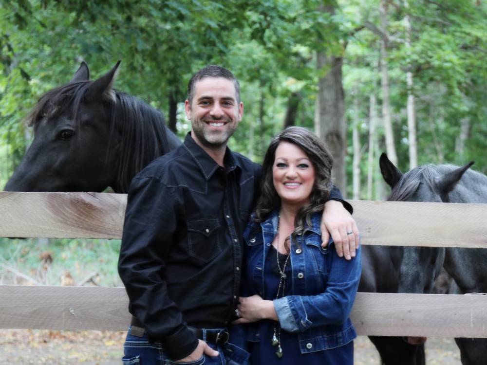 couple next to black horses